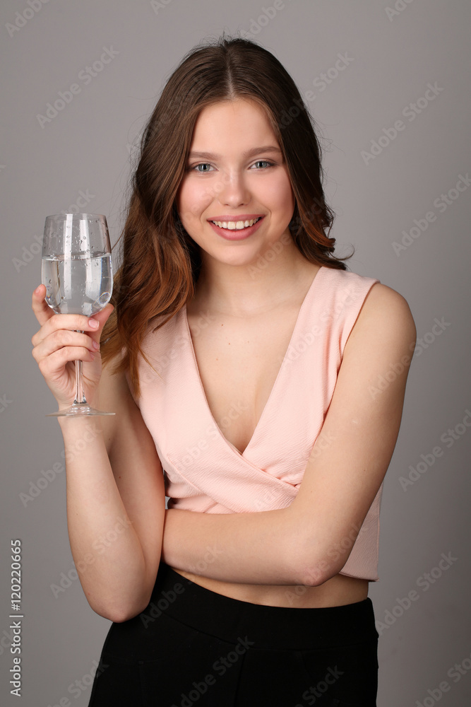 Lady posing with wine glass of water. Close up. Gray background Lady posing with wine glass of water. Close up. Gray background
