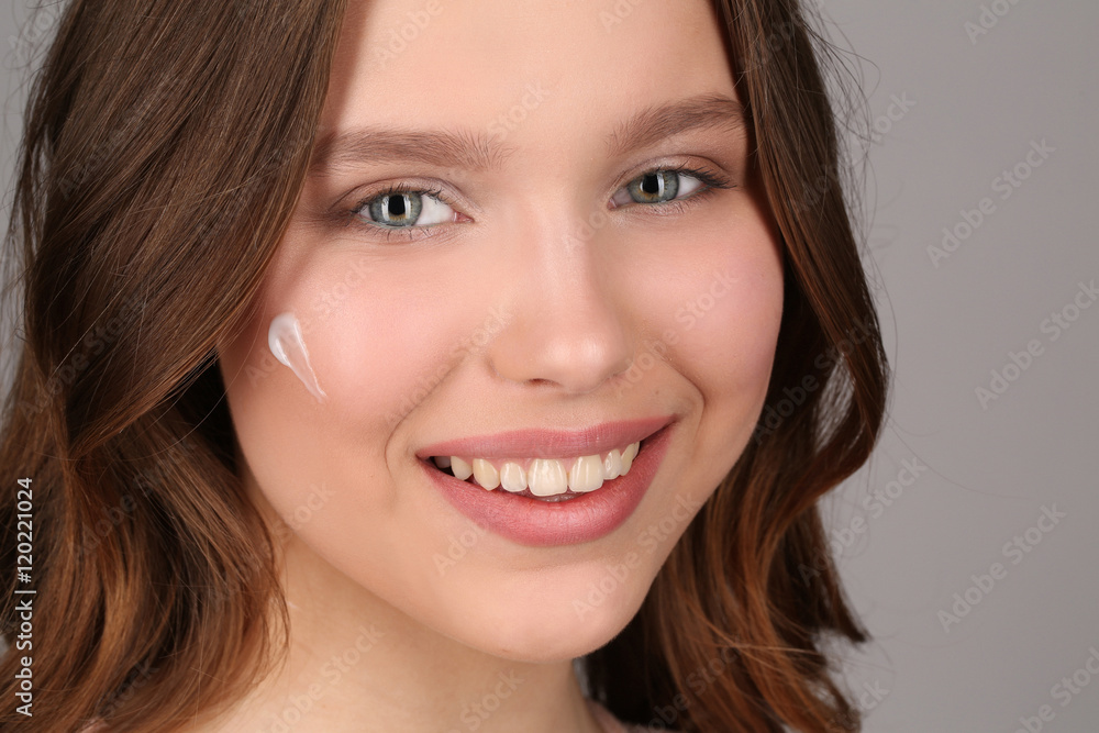 Model with makeup and cream on her face. Close up. Gray background Model with makeup and cream on her face. Close up. Gray background