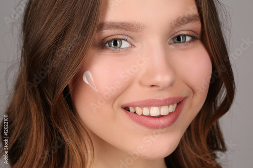 Teen with cream on her face. Close up. Gray background