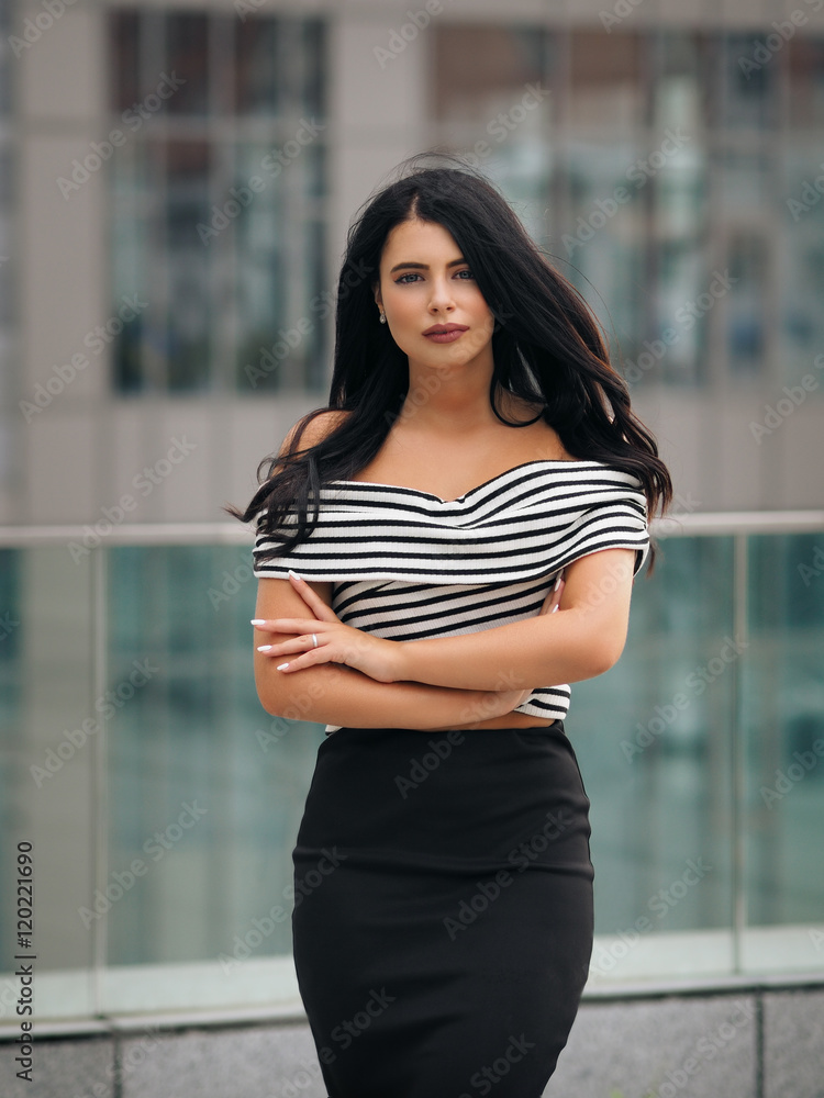 Fotografia do Stock: Portrait of young beautiful curvy woman plus size in  striped top and black skirt over blurred city background