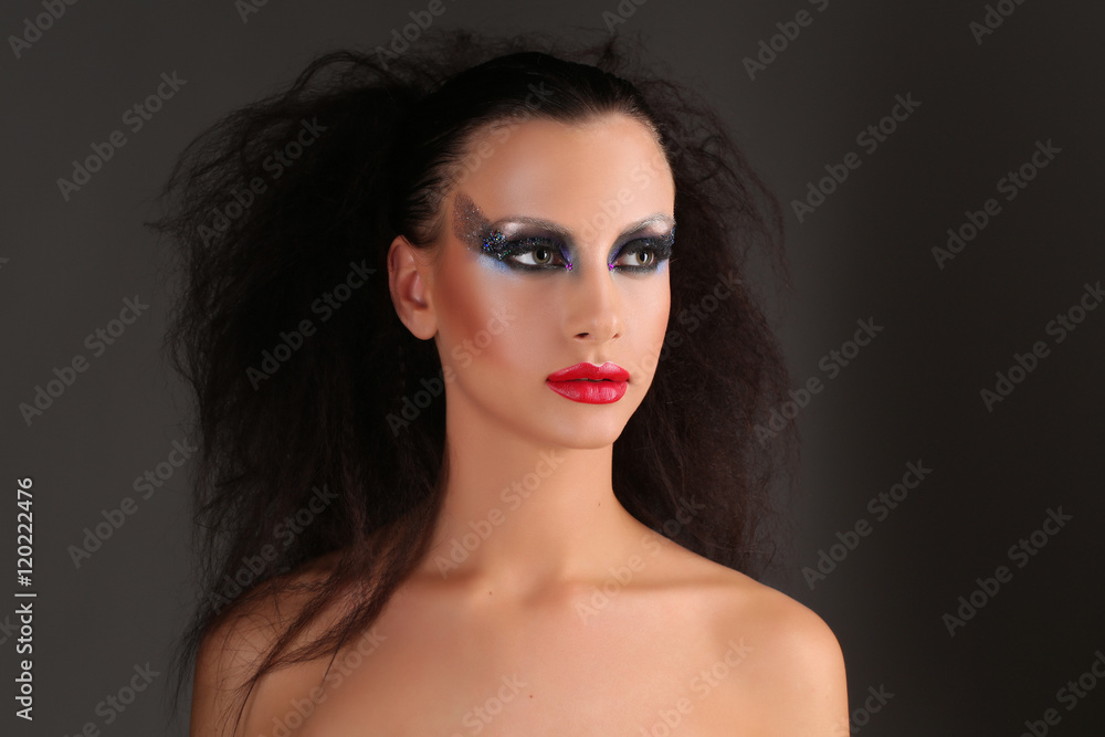 Fototapeta premium Naga kobieta z makijażem i dzikimi włosami. Ścieśniać. Szare tło