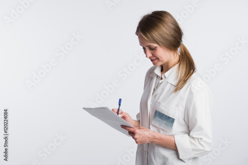 Cheerful medical doctor woman taking notes. Isolated on white
