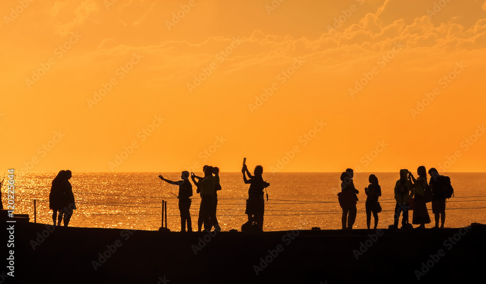 Silhouettes of people at sunset on the beach of Tanah Lot, Bali,