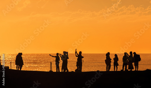 Silhouettes of people at sunset on the beach of Tanah Lot  Bali 