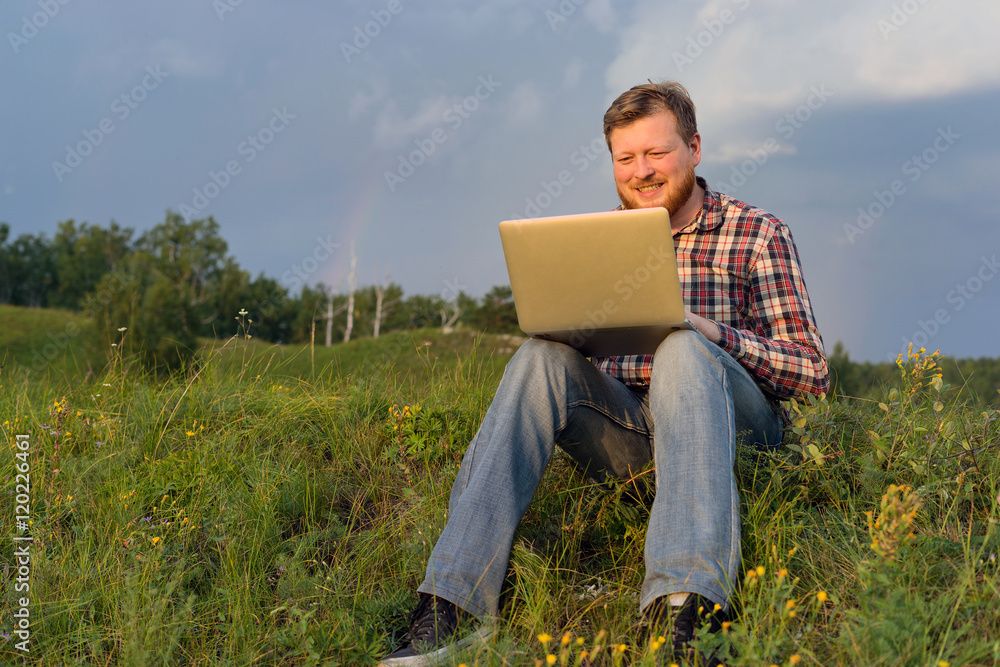 Man sitting on the grass with a laptop Man sitting on the grass with a laptop