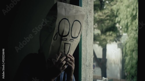 A shameful breadbag face near a window on a rainy day. Close-up shot.
 photo