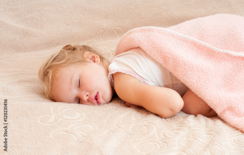 Beautiful sleeping child. Peaceful child lying on a bed in a bri Beautiful sleeping child. Peaceful child lying on a bed in a bri