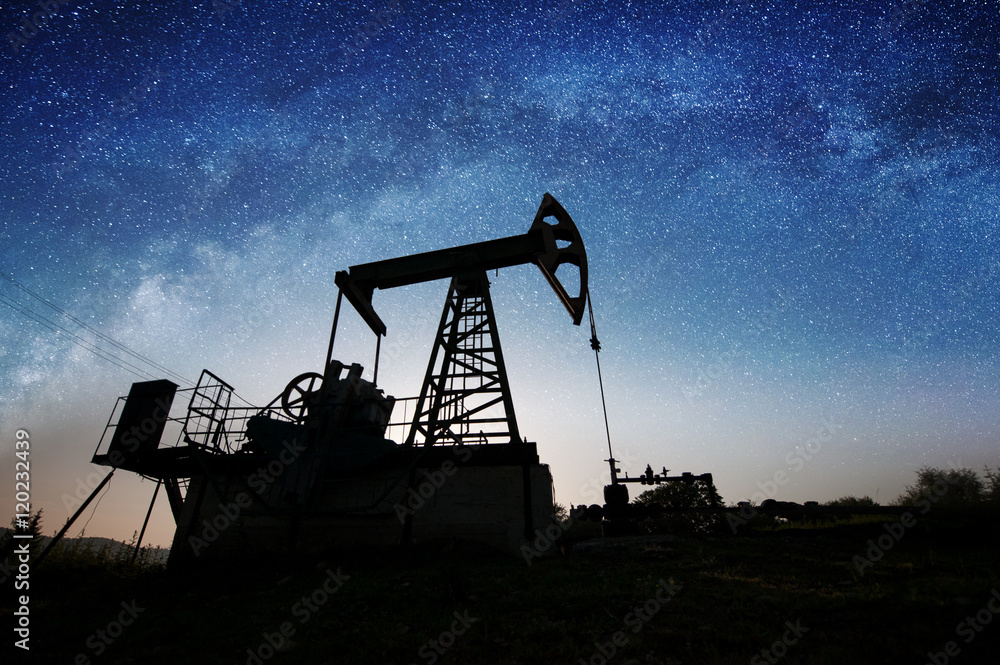 Silhouette of oil pump jack pumping on the oil field in the night with  starry sky galaxy. Milky way. Oil industry equipment Stock Photo