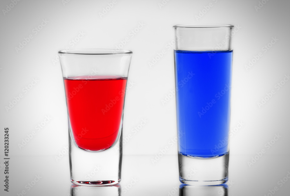 Two blue and red cocktail in full transparent shot glasses with Two blue and red cocktail in full transparent shot glasses with