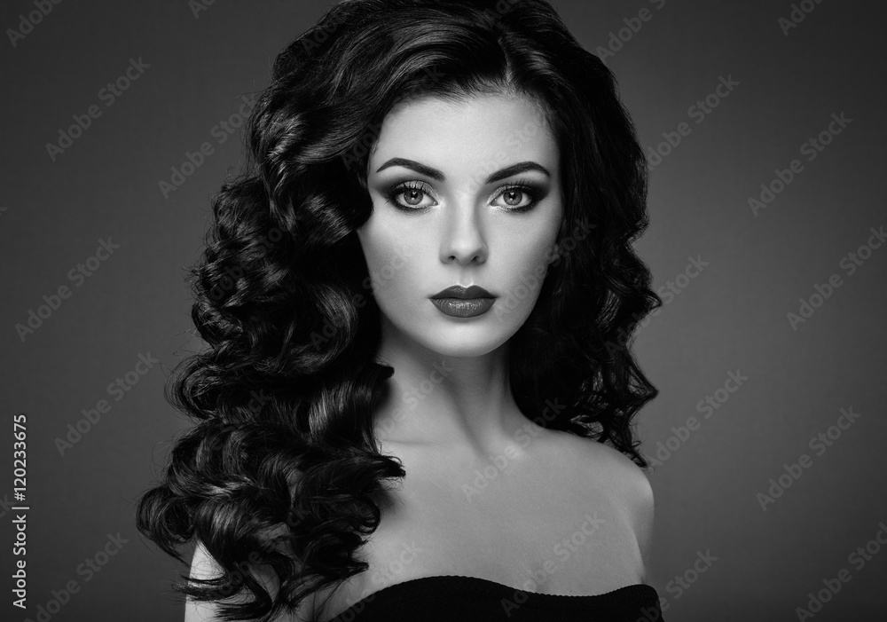Fototapeta premium Brunette woman with curly hairstyle. Beautiful girl with long wavy hair. Perfect makeup. Fashion photo. Black and White