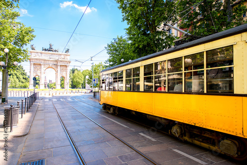 Street view with old yellow tram and Simplon city gate in Milan