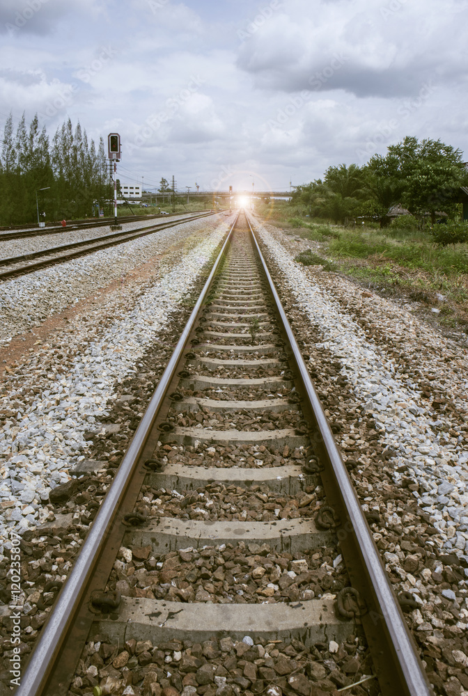 view of the length of railway with green tree at left and right side of railway.filtered image.light effect and flare added