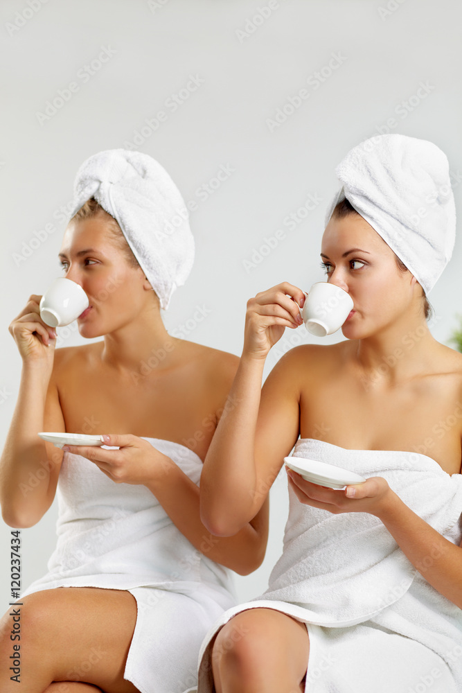 Portrait of two girls wrapped in towels drinking tea Portrait of two girls wrapped in towels drinking tea