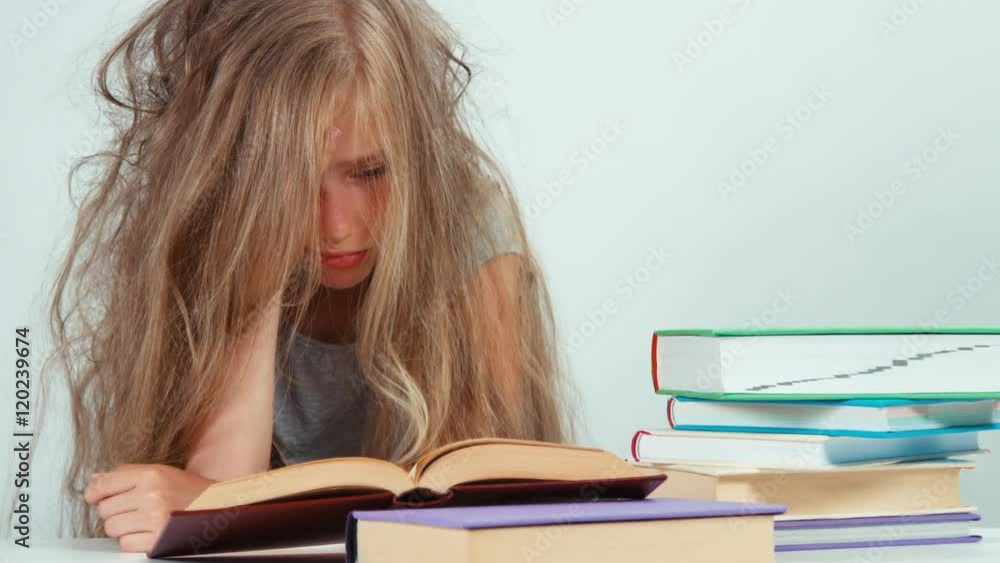 Portrait tired sad student girl 7-8 years old does not want to study and reading books