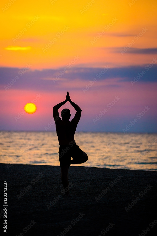 man practices yoga on the beach, the sea.