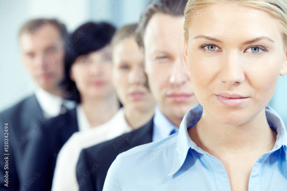 Young businesswoman looking at camera with her team on background Young businesswoman looking at camera with her team on background