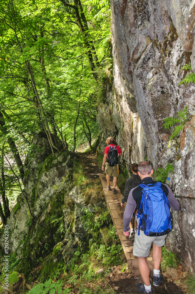 Wanderer begehen einen Pfad entlang einer steilen Felswand