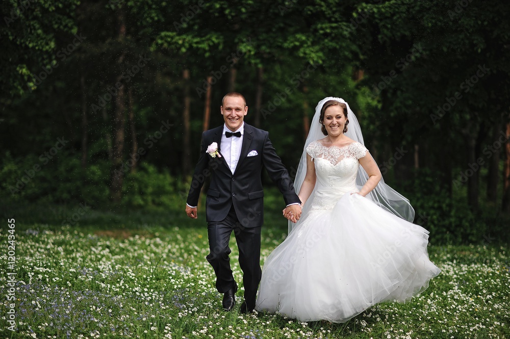 Happy newlyweds running at field of white flowers Happy newlyweds running at field of white flowers