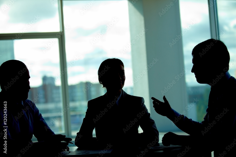 Three business people talking in dark office Three business people talking in dark office