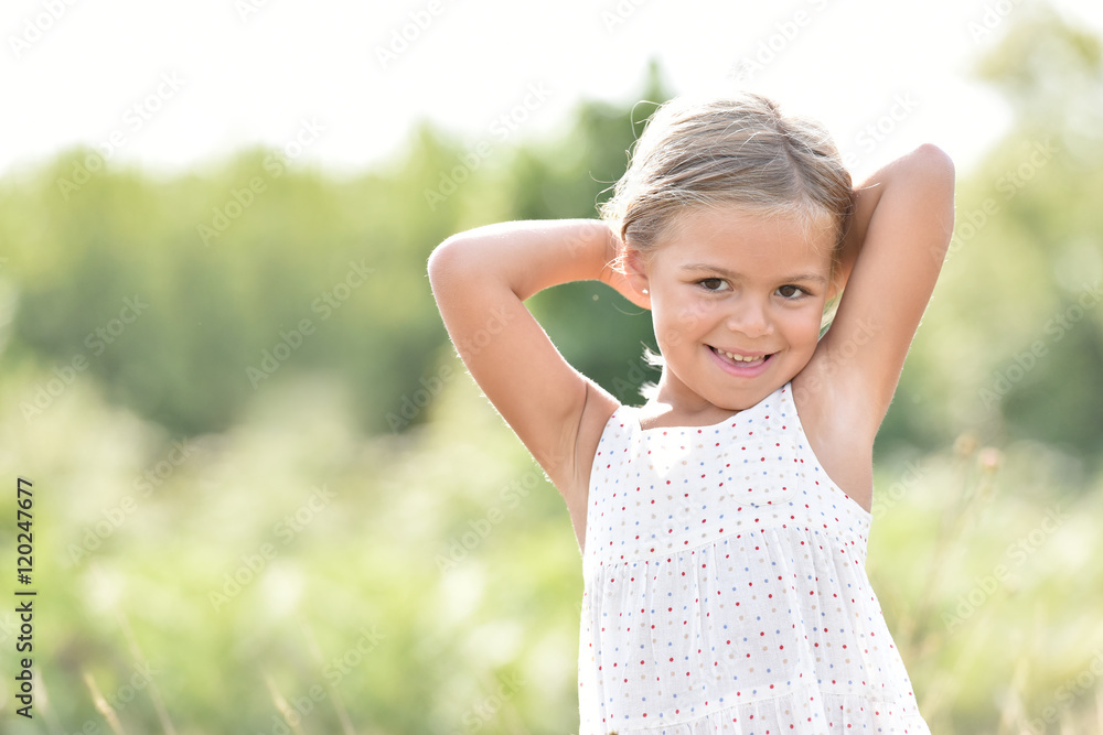 Portrait of cute little blond girl in countryside, summertime