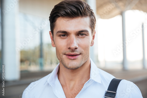 Closeup of smiling young businessman in white shirt standing outdoors