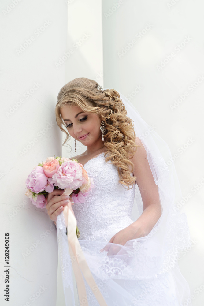 Beauty bride in bridal gown with bouquet and lace veil in the nature. Beautiful model girl in a white wedding dress. Female portrait in the park. Woman with hairstyle. Cute lady outdoors Beauty bride in bridal gown with bouquet and lace veil in the nature. Beautiful model girl in a white wedding dress. Female portrait in the park. Woman with hairstyle. Cute lady outdoors