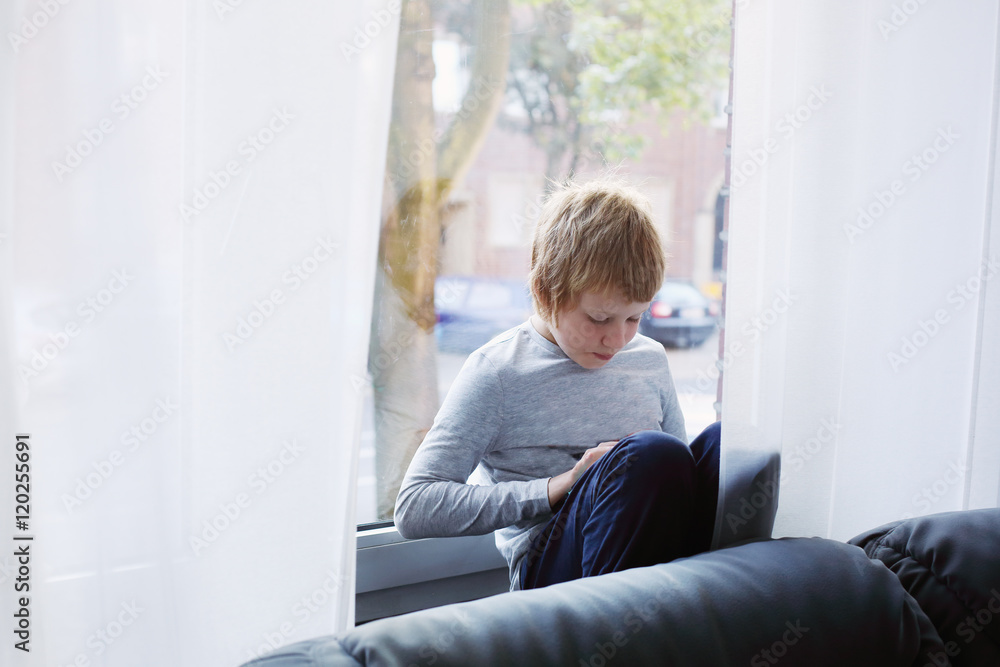 8 year old boy sitting near the window and playing with laptop 8 year old boy sitting near the window and playing with laptop