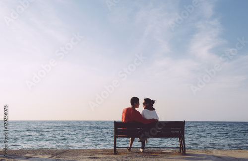 back portrait of young couple looking at each other on bench by the sea in Kusadas, Turkey, clean composition   © sweetriver