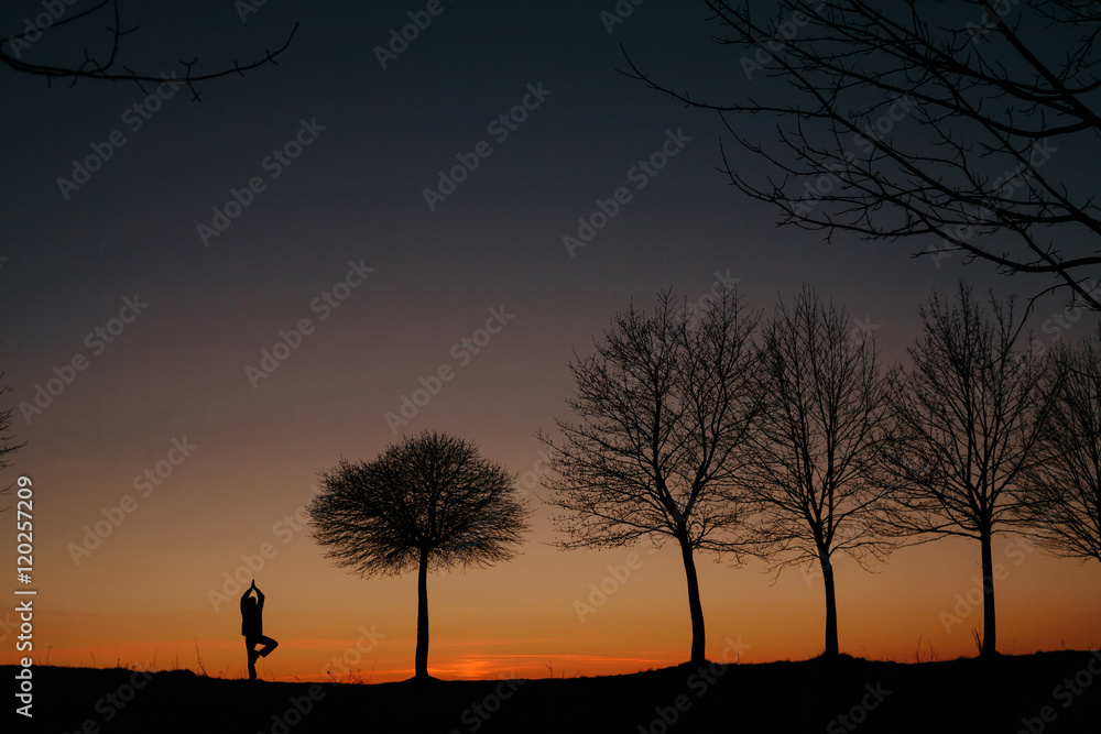 silhouette of a man who practices yoga at sunset