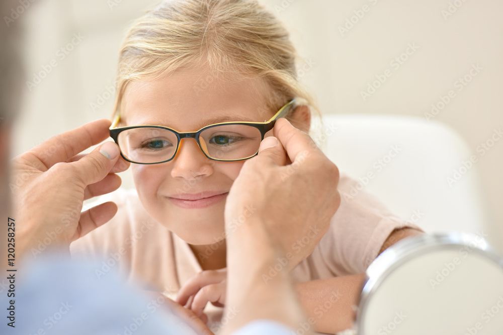 Little girl at the optician trying different eyeglasses Little girl at the optician trying different eyeglasses