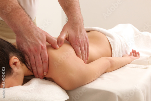 Masseur doing massage on woman body in the spa salon.