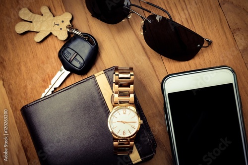 Top view of lady set: watches, car keys, sunglasses,and smart phone on wooden