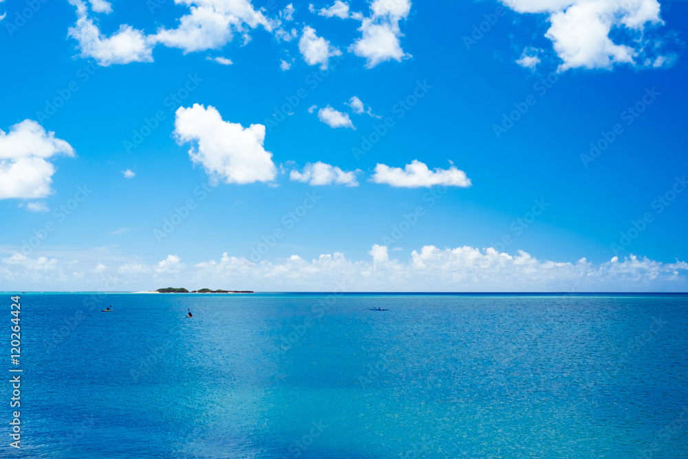 沖縄の青い海に浮かぶカヌーと小島
