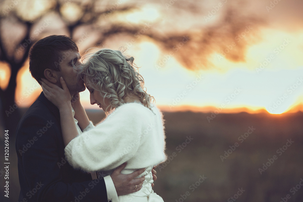 grom is kissing his bride very tender on forehed on beckground r
