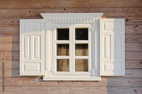 Wooden window with beautiful white shutters under olden. Wall of the rural house.