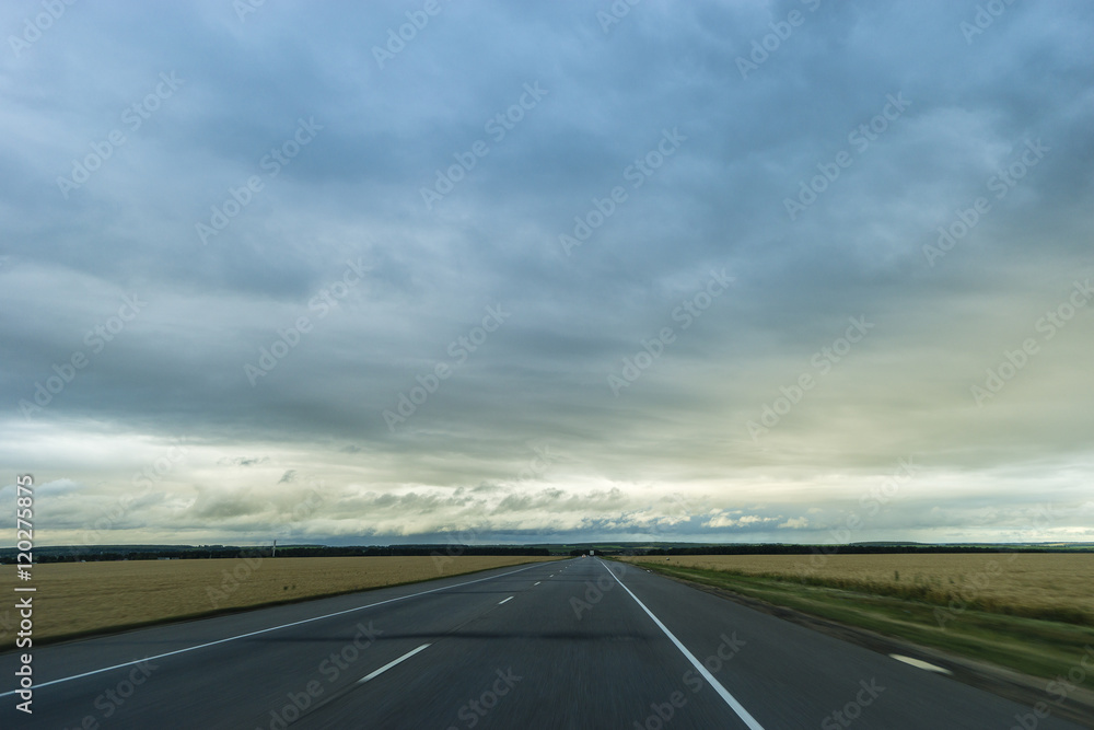 Summer day landscape with road and rainy cloudy sky