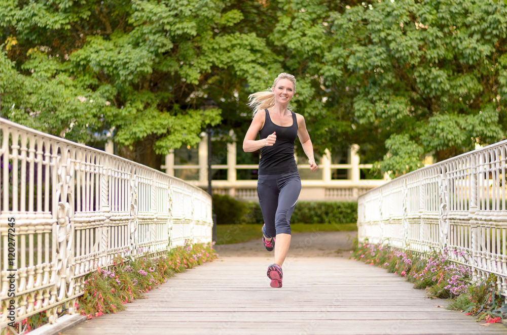Fit active woman running across a bridge
