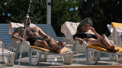 The man and girl relax near the swimming pool