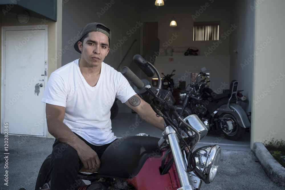 Motorist posing with his motorcycle on the garage Motorist posing with his motorcycle on the garage