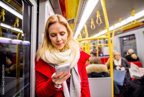 Photography Beautiful young woman with smart phone in subway train