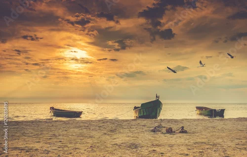 Obraz łódki zacumowane przy brzegu na tle zachodzącego słońce