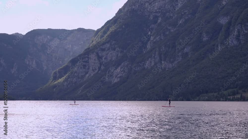 Unrecognizable people paddle boarding on lake Bohinj in Slovenian Triglav national park. Unrecognizable people paddle boarding on lake Bohinj in Slovenian Triglav national park.