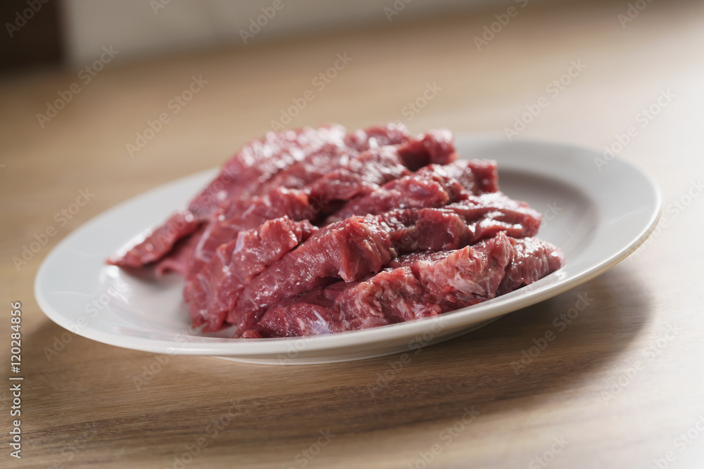 raw fresh sliced beef for beefsteaks in plate on kitchen table raw fresh sliced beef for beefsteaks in plate on kitchen table