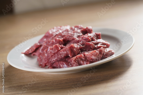 raw fresh sliced beef for beefsteaks in plate on kitchen table
