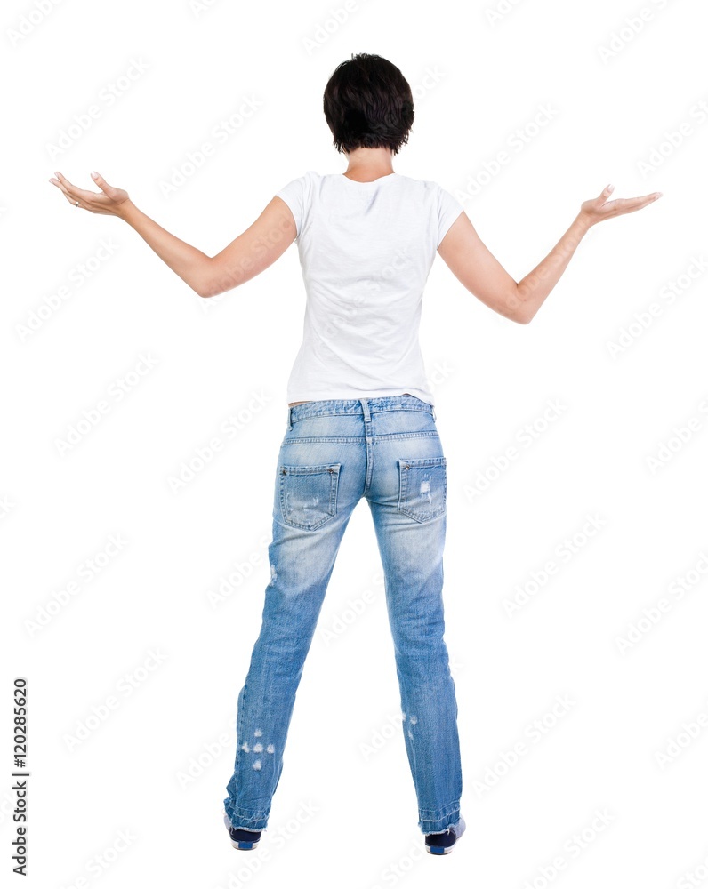 Back view of Beautiful woman in jeans looking at wall and Holds hand up. young brunette girl standing. Rear view people. Isolated over white background. Back view of Beautiful woman in jeans looking at wall and Holds hand up. young brunette girl standing. Rear view people. Isolated over white background.