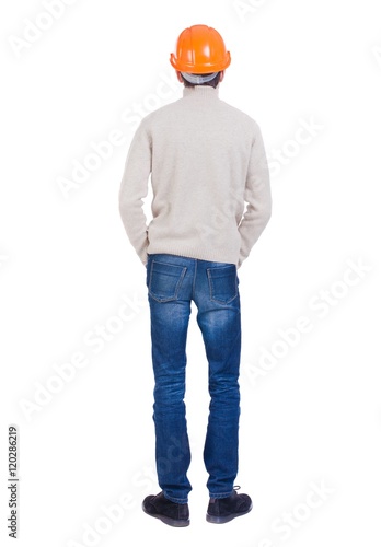 Backview of an engineer in construction helmet stands. Standing young guy. Rear view people collection.  backside view of person.  Isolated over white background. Engineer in a warm jacket is folded © ghoststone
