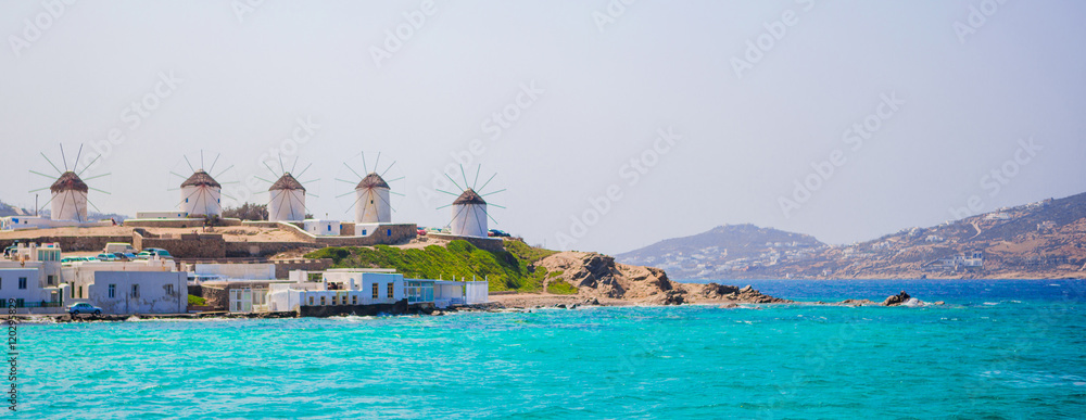 Naklejka premium Panorama of famous view of traditional greek windmills on Mykonos island at sunrise, Cyclades, Greece