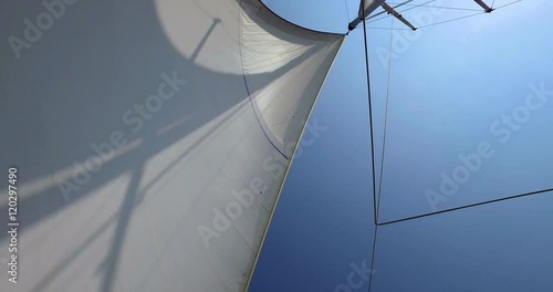 Large yacht sail blowing in the wind on a blue sky day