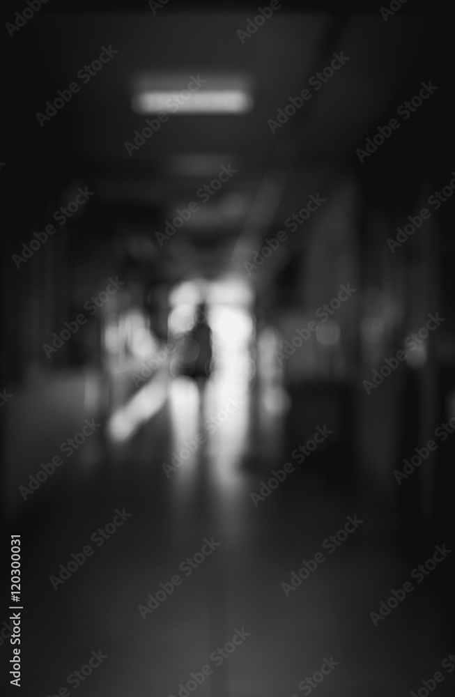 Blurred image of a people working in an hospital in walking away in a under passage to the light. Black and white image. Motion blur