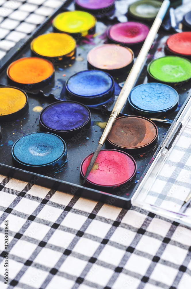 Naklejka premium Watercolor equipment, paint, paper and brushes on table